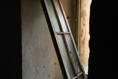 Terk edilmiş bir binada yıpranmış beyaz boya ile eski bir pencere, mimari bozulmayı ve atmosferik aydınlatmada dokulu duvarları gösteriyor