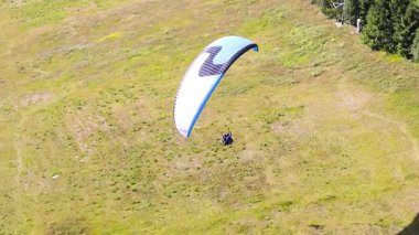 İnsanlar rüzgarı yakalar ve yerden yükseklerde bir planörde uçarlar. Paragliding aşırı bir spordur. Paraşütçü bir adamın dağların üzerinden uçuşu..