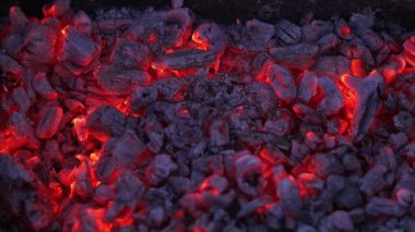 Sıcak kömüre dönüşen yanmış odunlara yakın çekim. Küçük kömürler titreşir ve sıcak hava etraflarında hareket eder. Şenlik ateşi, barbekü ya da soba için yakıt olarak kullanılıyor..