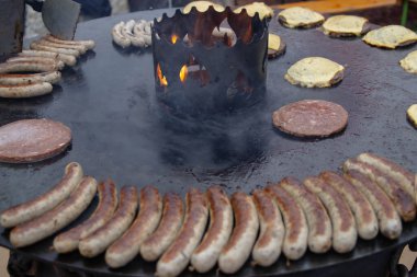 Büyük yuvarlak bir tavada sucuklu sosis pişirmek. Merkezde canlı bir ateş yanar ve tüm yüzeyi ısıtır. Açık havada sıcak sandviçler için doğal sosis ve pirzola. Çeşitli tatil fuarlarında geleneksel Alman yemekleri.