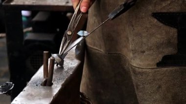 Demirci metal bir gül yapar. Erkek eller kerpetenle çalışır. Çiçek yapmak için yaprakları bükerler..