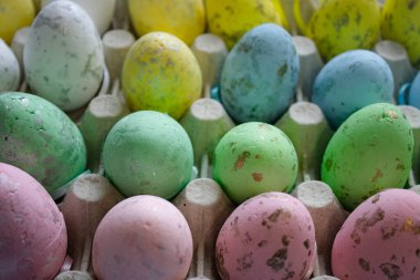 Paskalya dekoratif paskalya yumurtalarını yakından çek. Yumurtalar çeşitli pastel renklerde boyanmıştır. Doğal bıldırcın ya da diğer kuş yumurtalarının görünümünü taklit eden benekli bir dokuları var. Yumurtalar yatay olarak dizilmiş..