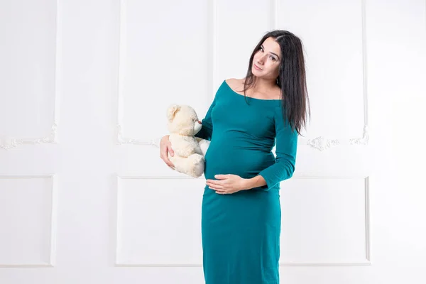 Беременная девушка с плюшевым мишкой в руках — стоковое фото
