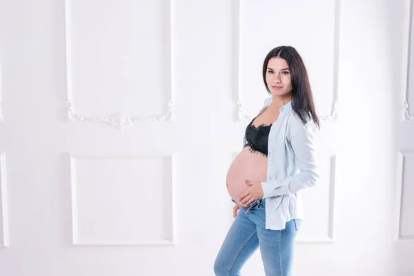 Chica embarazada feliz en jeans y camisa desabotonada —  Fotos de Stock