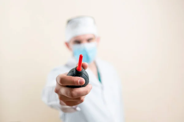 Doctor in mask and glasses shows an enema. High quality photo