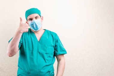 Maskeli ve şapkalı doktor, baş parmağını kaldırıyor..