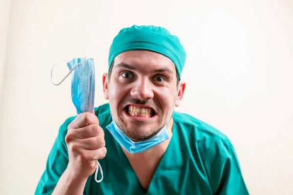 Funny doctor with a medical mask in his hands. — Stock Photo, Image