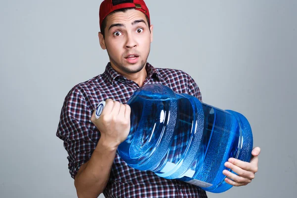 Entrega de água. Alegre jovem entregador segurando uma água — Fotografia de Stock