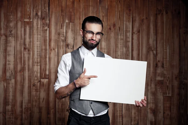 Стильный парень с белым знаком для текста на деревянном фоне , — стоковое фото