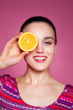 Yüzünün yanında turuncu yarımlar tutan komik mutlu kız portresi.,