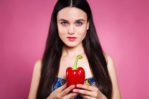 Hermosa chica en el estudio sobre un fondo rosa con pimienta . — Foto de Stock