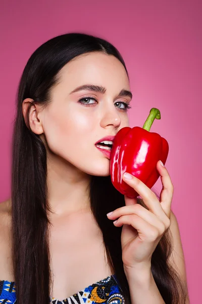 Menina bonita no estúdio em um fundo rosa com pimenta . — Fotografia de Stock