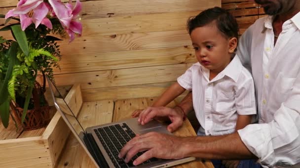 Vater unterrichtet seinen Sohn am Laptop — Stockvideo