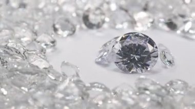 Çeşitli boyutlarda beyaz elmaslar, beyaz elmaslarla çevrili beyaz bir arka planda dönen bir merkez daireye yerleştirilir..