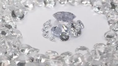 Çeşitli boyutlarda beyaz elmaslar, beyaz elmaslarla çevrili beyaz bir arka planda dönen bir merkez daireye yerleştirilir..