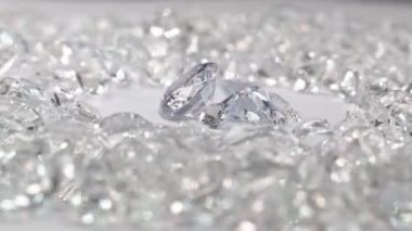 Çeşitli boyutlarda beyaz elmaslar, beyaz elmaslarla çevrili beyaz bir arka planda dönen bir merkez daireye yerleştirilir..