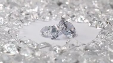 Çeşitli boyutlarda beyaz elmaslar, beyaz elmaslarla çevrili beyaz bir arka planda dönen bir merkez daireye yerleştirilir..