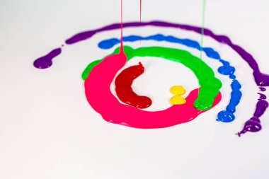 Beyaz dairesel arkaplan üzerinde çeşitli renkler düşer ve birlikte akar.