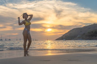 Sahilde gün batımında oynayan kadın. COVID-19 salgını sırasında Nai Harn sahilinde fazla turist yoktu. Ama yine de Nai Harn sahilinde Phuket Tayland 'da yerel halk var.