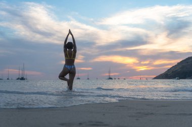 Sahilde gün batımında oynayan kadın. COVID-19 salgını sırasında Nai Harn sahilinde fazla turist yoktu. Ama yine de Nai Harn sahilinde Phuket Tayland 'da yerel halk var.