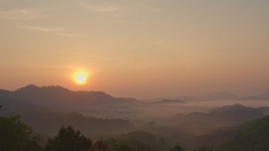 Büyük sarı güneş, sabah dağın zirvesinin üstündeki kırmızı gökyüzünde parlıyor. Phang Nga Eyaleti 'nin birçok büyük ve küçük tepeleri vardır. Ve sabahları yağışlı hava genellikle bir sis denizi yaratır..