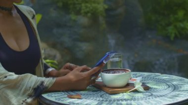 Kahve setiyle cep telefonuyla oynayan bir bayan.