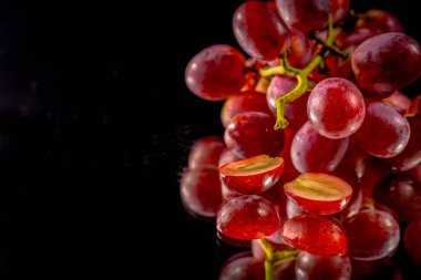 Üzümler siyah bir arka planla aynanın yarısından kesilmiş.