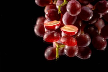 Üzümler siyah bir arka planla aynanın yarısından kesilmiş.