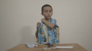 Tatlı çocuk beyaz bir arka planda beyaz bir atletin üzerine Hawaii gömleği giymekten hoşlanıyordu. Stüdyoda Kara Büyü 6K kamerasıyla çekim yap..