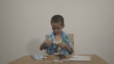 Tatlı çocuk beyaz bir arka planda beyaz bir atletin üzerine Hawaii gömleği giymekten hoşlanıyordu. Stüdyoda Kara Büyü 6K kamerasıyla çekim yap..