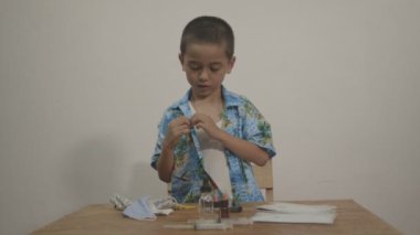 Tatlı çocuk beyaz bir arka planda beyaz bir atletin üzerine Hawaii gömleği giymekten hoşlanıyordu. Stüdyoda Kara Büyü 6K kamerasıyla çekim yap..