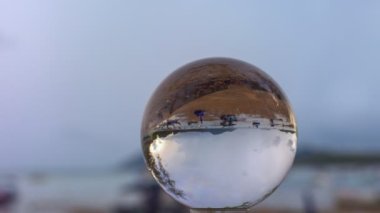 Deniz kenarındaki kristal küreye yağmur yağıyor.