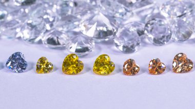 Kalp şeklinde renkli elmas beyaz elmas arka planda bir sıraya konur.,