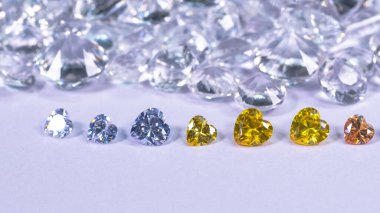 Kalp şeklinde renkli elmas beyaz elmas arka planda bir sıraya konur.,