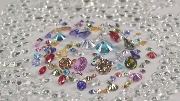 白いダイヤモンドの背景を持つ白い床に置かれたカラフルな宝石 高品質のビデオショット — ストック動画