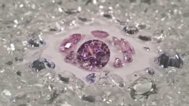 Pembe safir elmaslar farklı boyutlarda ve birçok şekil ortadaki beyaz zeminde kesilmemiş kırmızı taşlarla çevrili. 