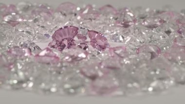 Pembe safir elmaslar farklı boyutlarda ve birçok şekil ortadaki beyaz zeminde kesilmemiş kırmızı taşlarla çevrili. 
