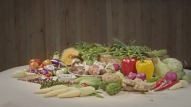 Sağlıklı vejetaryen yemek malzemeleri hazırlıyorum. Taze sebzeler, baharatlar ve farklı türde mantarlar arka planda ahşap bir sahne ile beyaz bir masaya yerleştirilir. yüksek kaliteli 4K video