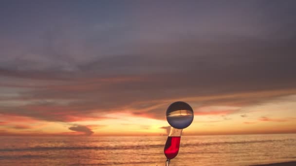 Deniz Manzaralı Kırmızı Şarap Kadehinin Ağzında Kristal Gülle Günbatımı Arka — Stok video