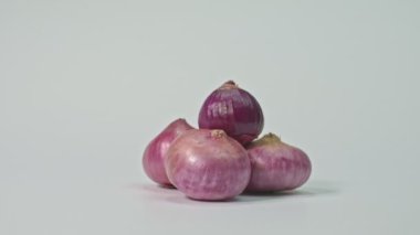 Kırmızı soğanın biraz daha tatlı tadı sağlıklı organik narları bitirir. Beyaz arka planda yüksek kaliteli 4K Shallots videosu. Stüdyo çekimi.
