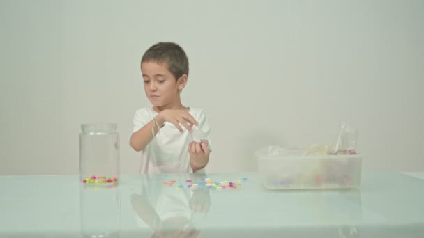 Een Leuke Jongen Speelde Gelukkig Veelkleurige Kralen Witte Kamer Hoge — Stockvideo