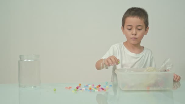 Een Leuke Jongen Speelde Gelukkig Veelkleurige Kralen Witte Kamer Hoge — Stockvideo