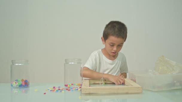 Egy Aranyos Fiú Boldogan Játszott Sokszínű Gyöngyök Fehér Szobában Kiváló — Stock videók