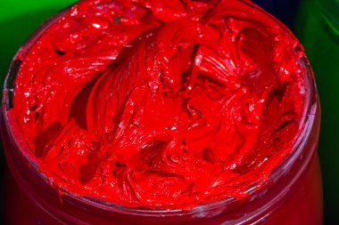 Cam kovadaki kırmızı boya cam kovadaki baskı tişörtü için kırmızı plastisol mürekkebi. Renkli mürekkep arkaplanı.