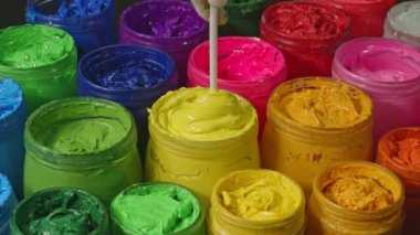 Cam kovadaki mastik boyayı karıştırmak için bir kaşık kullan. Yüksek kalite 4K video. Renkli mürekkep arkaplanı.