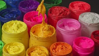 Cam kovadaki sarı boyayı karıştırmak için bir kaşık kullan. Yüksek kalite 4K video. Renkli mürekkep arkaplanı.