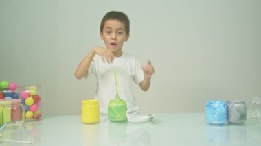 Bir çocuk sevinçle yeni bir rengi karıştırıyordu. Çocuk okulda renkleri karıştırıyordu, çocukların yönettiği Montessori metodu. Yüksek kaliteli 4K video stüdyosu. renkli arkaplan.