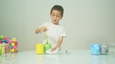 Bir çocuk sevinçle yeni bir rengi karıştırıyordu. Çocuk okulda renkleri karıştırıyordu, çocukların yönettiği Montessori metodu. Yüksek kaliteli 4K video stüdyosu. renkli arkaplan.