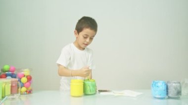 Bir çocuk sevinçle yeni bir rengi karıştırıyordu. Çocuk okulda renkleri karıştırıyordu, çocukların yönettiği Montessori metodu. Yüksek kaliteli 4K video stüdyosu. renkli arkaplan.
