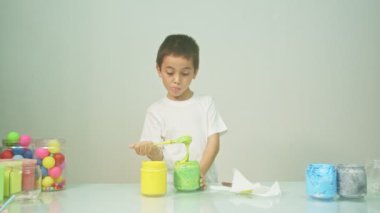 Bir çocuk sevinçle yeni bir rengi karıştırıyordu. Çocuk okulda renkleri karıştırıyordu, çocukların yönettiği Montessori metodu. Yüksek kaliteli 4K video stüdyosu. renkli arkaplan.